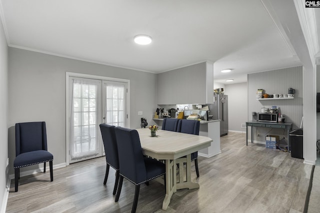 dining area featuring baseboards, crown molding, and light wood-type flooring