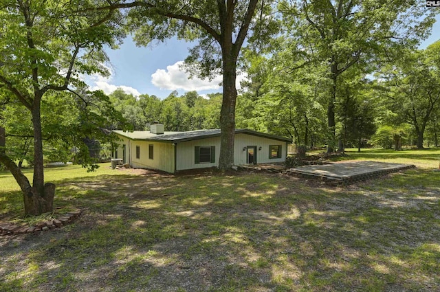 rear view of house with a chimney and a yard