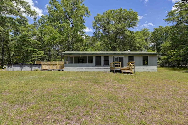 rear view of property featuring a lawn, a sunroom, and an outdoor pool