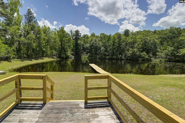 deck with a wooded view, a water view, and a lawn