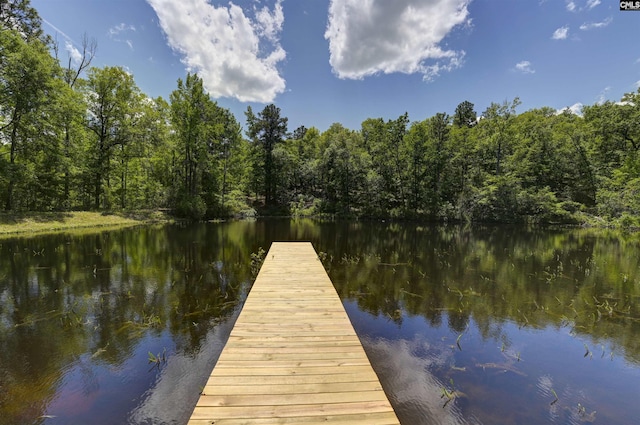 view of dock featuring a wooded view and a water view