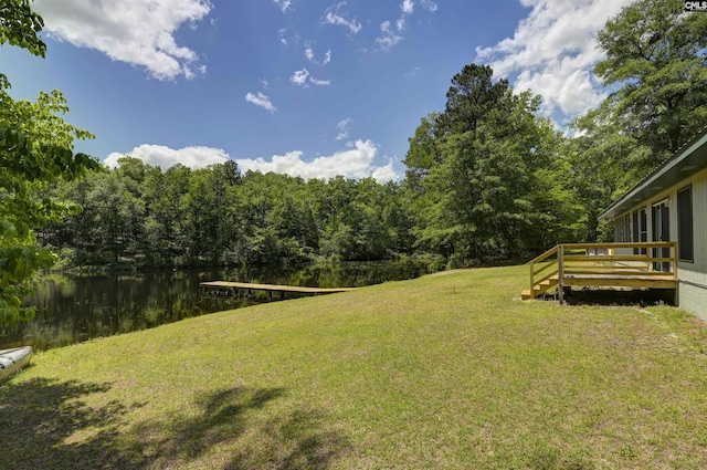 view of yard featuring a wooded view and a deck with water view