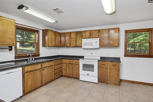 kitchen with a sink, brown cabinets, white appliances, and a wealth of natural light