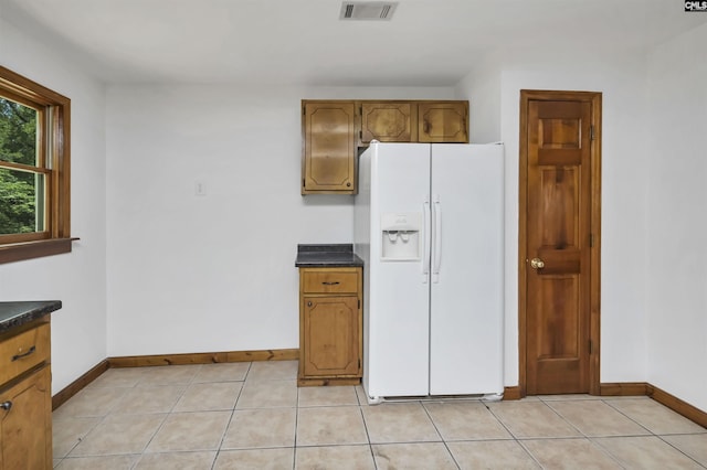 kitchen featuring white refrigerator with ice dispenser, baseboards, dark countertops, and visible vents