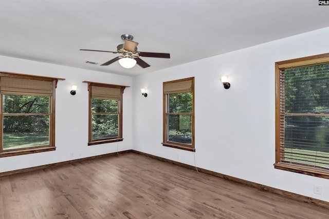 spare room with baseboards, visible vents, a ceiling fan, and wood finished floors