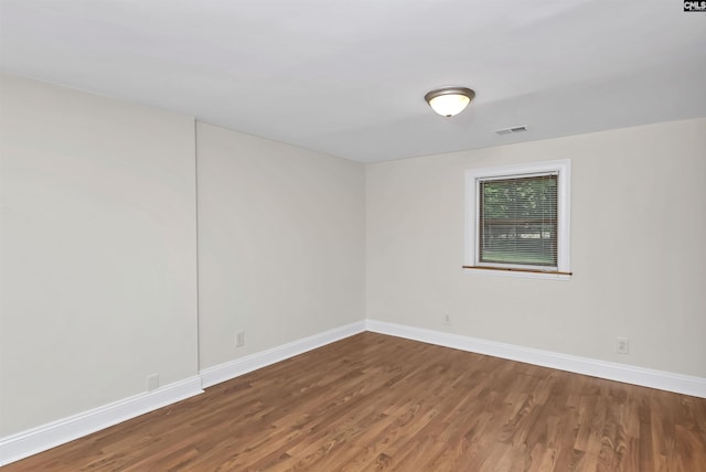 spare room with baseboards, visible vents, and wood finished floors