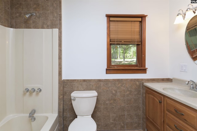 full bath featuring shower / bathing tub combination, tile walls, toilet, vanity, and wainscoting