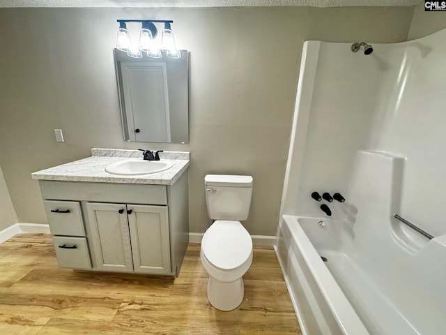 full bath with toilet, wood finished floors, vanity, shower combination, and baseboards