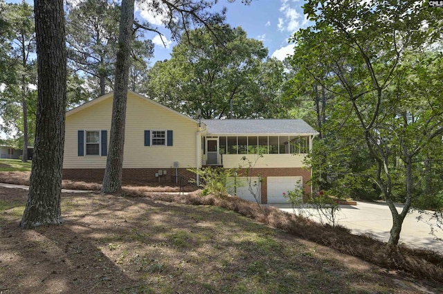 view of front of house featuring a sunroom, concrete driveway, and a garage