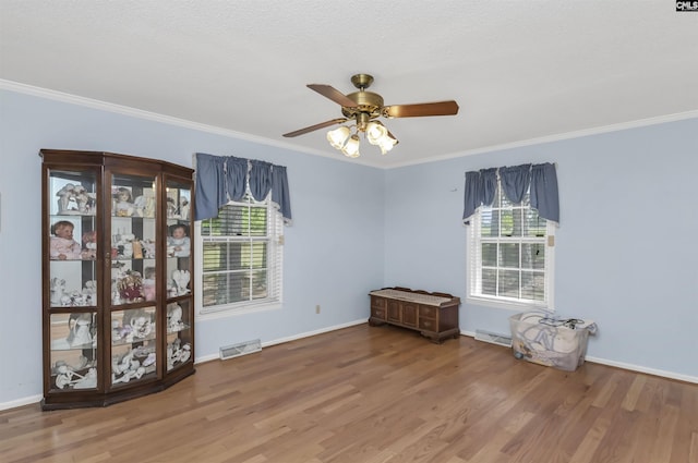 spare room with a wealth of natural light, crown molding, and wood finished floors