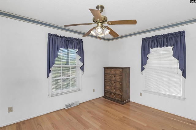 spare room with ceiling fan, visible vents, and wood finished floors