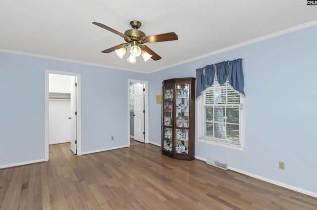 unfurnished bedroom with ornamental molding, baseboards, visible vents, and wood finished floors