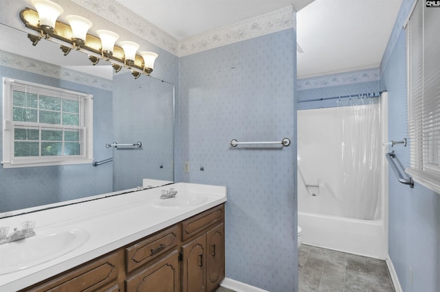 full bathroom with baseboards, toilet, double vanity, and a sink
