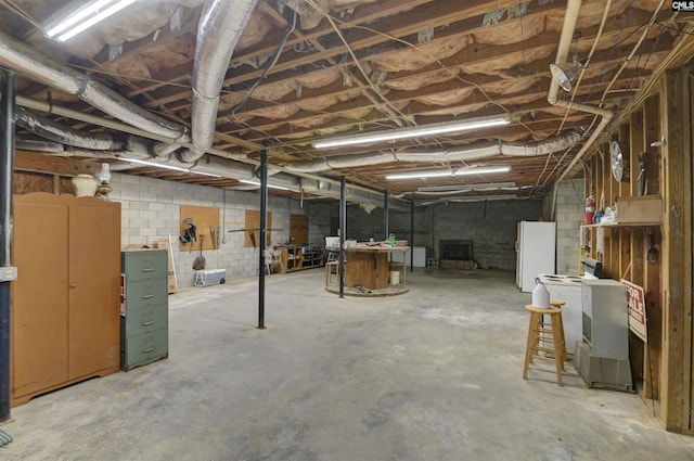 unfinished below grade area with freestanding refrigerator and concrete block wall