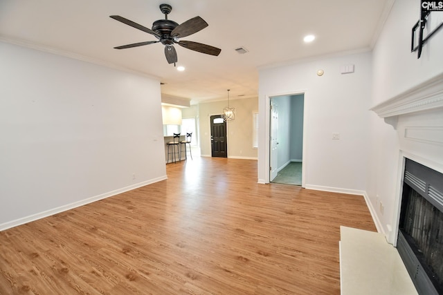 unfurnished living room featuring crown molding, light wood-type flooring, visible vents, and a fireplace with flush hearth