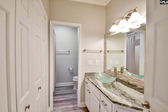 full bath featuring toilet, wood finished floors, crown molding, baseboards, and vanity