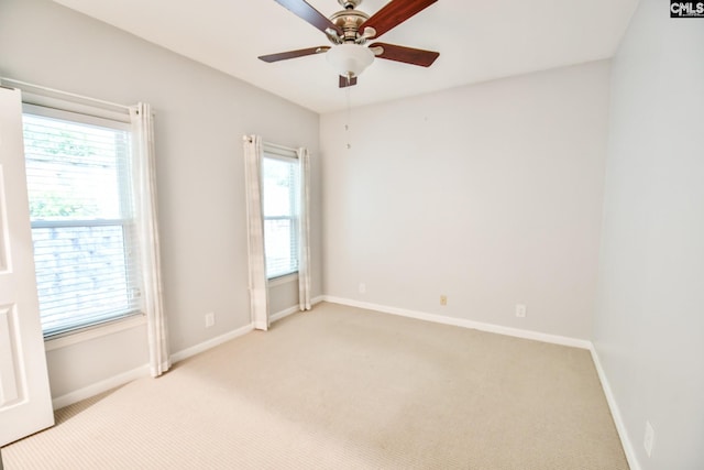 empty room featuring a wealth of natural light, light carpet, and baseboards