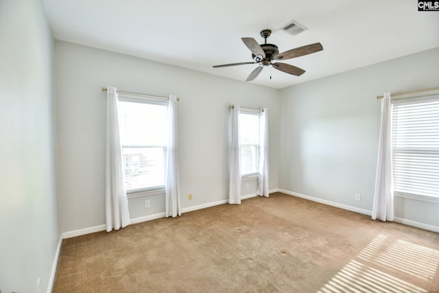 empty room with visible vents, baseboards, a ceiling fan, and carpet floors