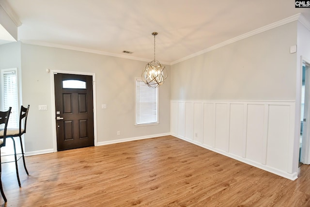 entryway featuring a notable chandelier, crown molding, visible vents, wainscoting, and light wood-style floors