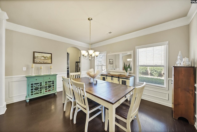 dining room featuring an inviting chandelier, a wainscoted wall, crown molding, arched walkways, and dark wood-style floors