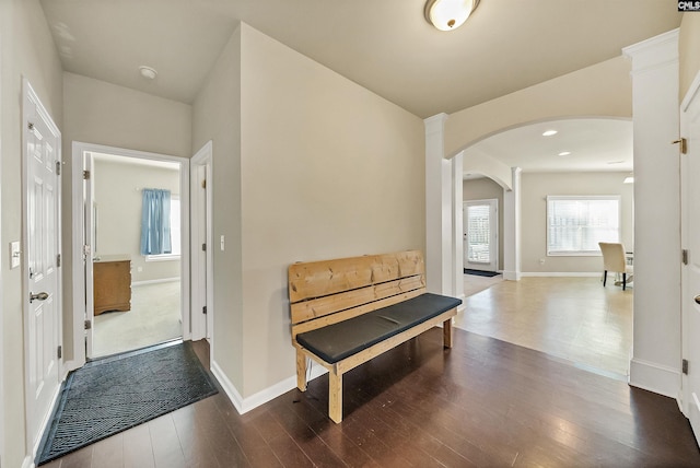 hallway featuring arched walkways, baseboards, and dark wood-type flooring