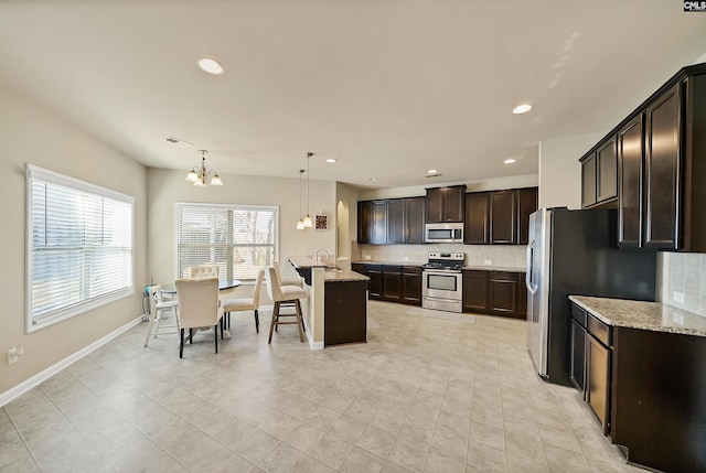 kitchen featuring appliances with stainless steel finishes, a chandelier, a sink, and backsplash