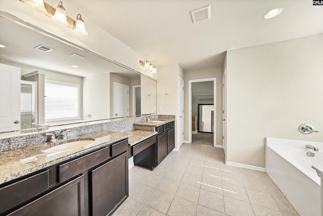 bathroom with double vanity, a bath, visible vents, and a sink