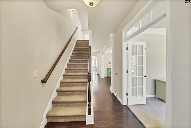 stairs with wood finished floors, baseboards, and arched walkways