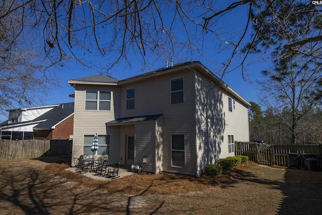 back of house with a fenced backyard and a patio