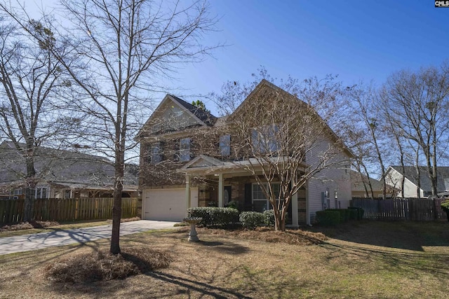 traditional-style house with a porch, concrete driveway, an attached garage, and fence