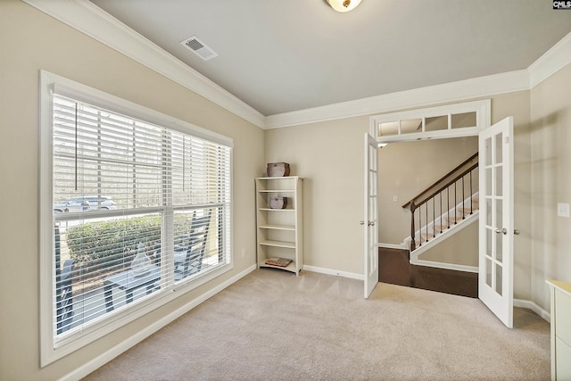 empty room with carpet, french doors, crown molding, visible vents, and baseboards