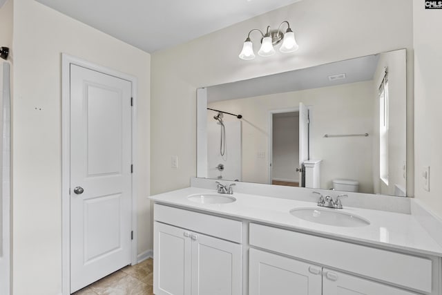 bathroom featuring toilet, double vanity, a shower, and tile patterned flooring