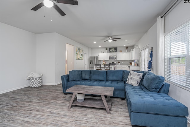living area featuring a ceiling fan, light wood-style floors, baseboards, and recessed lighting