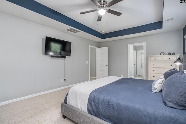 carpeted bedroom featuring baseboards, a raised ceiling, and a ceiling fan