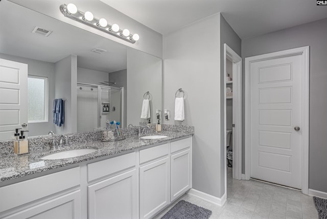 bathroom featuring a stall shower, double vanity, baseboards, and toilet