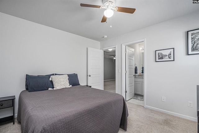 bedroom featuring light carpet, baseboards, ensuite bathroom, and a ceiling fan