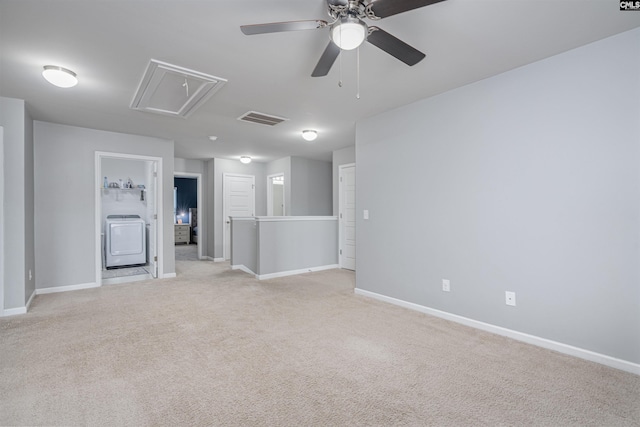 spare room featuring attic access, washer / dryer, light carpet, baseboards, and ceiling fan