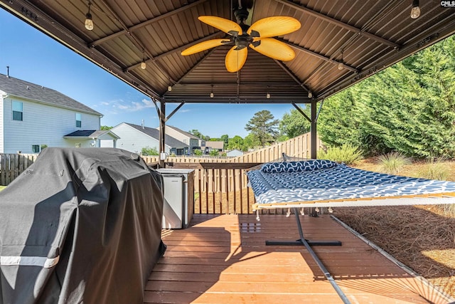 wooden deck featuring a gazebo, a ceiling fan, a grill, and a residential view