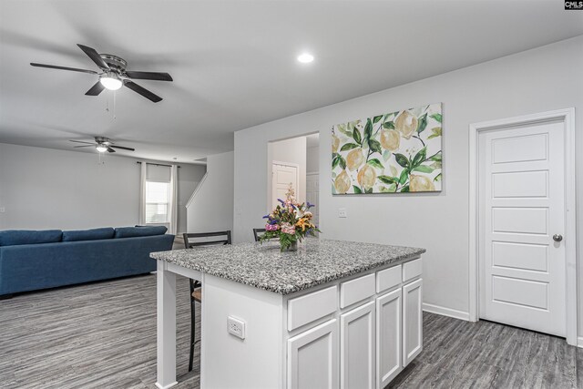 kitchen featuring a ceiling fan, wood finished floors, white cabinets, a kitchen island, and open floor plan