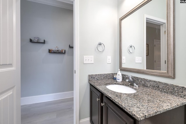 bathroom with baseboards, vanity, and wood finished floors