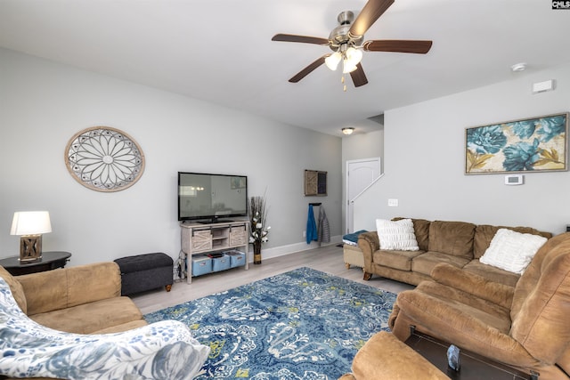 living area with a ceiling fan, light wood-type flooring, and baseboards