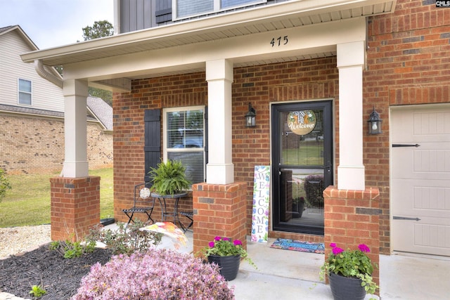 entrance to property featuring covered porch and brick siding