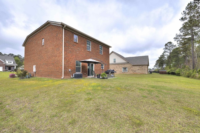 rear view of property featuring brick siding, cooling unit, and a yard