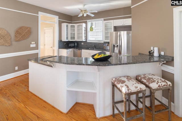 2408 Park St, Columbia, SC 29201 - kitchen with appliances with stainless steel finishes, a peninsula, glass insert cabinets, a sink, and white cabinets