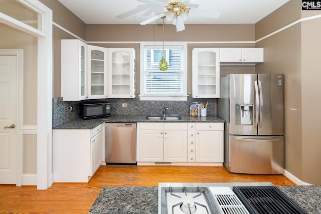 2408 Park St, Columbia, SC 29201 - kitchen with stainless steel appliances, a sink, white cabinets, light wood-style flooring, and decorative backsplash