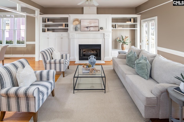 2408 Park St, Columbia, SC 29201 - living area with light wood-type flooring, ceiling fan, a fireplace with raised hearth, and baseboards