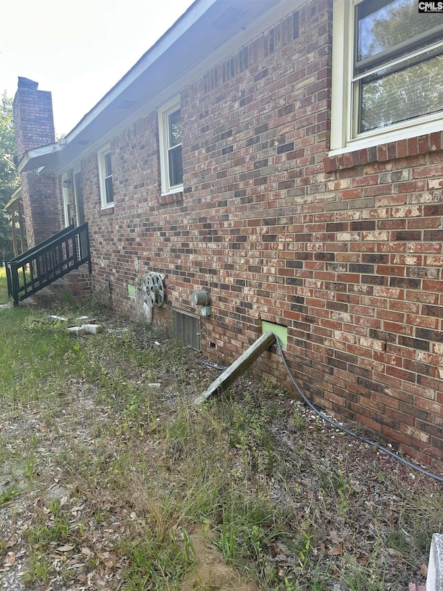 view of property exterior with a chimney and brick siding