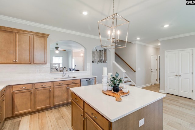 kitchen with a sink, brown cabinetry, light countertops, a kitchen island, and crown molding