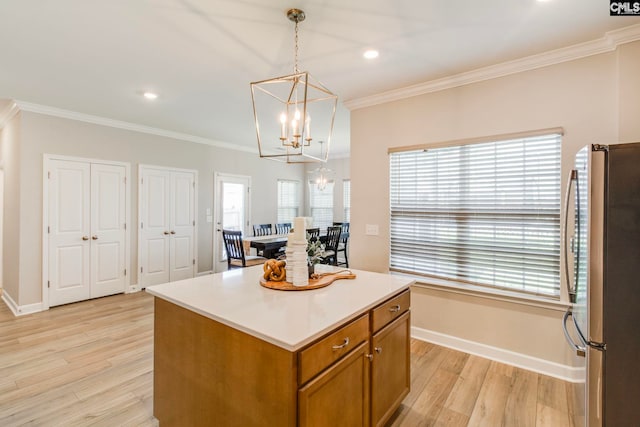 kitchen with freestanding refrigerator, a chandelier, light wood finished floors, brown cabinets, and ornamental molding