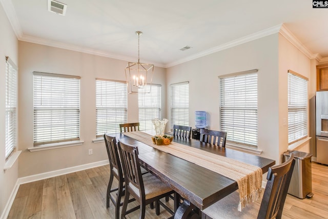 dining space featuring a chandelier, light wood finished floors, healthy amount of natural light, baseboards, and ornamental molding